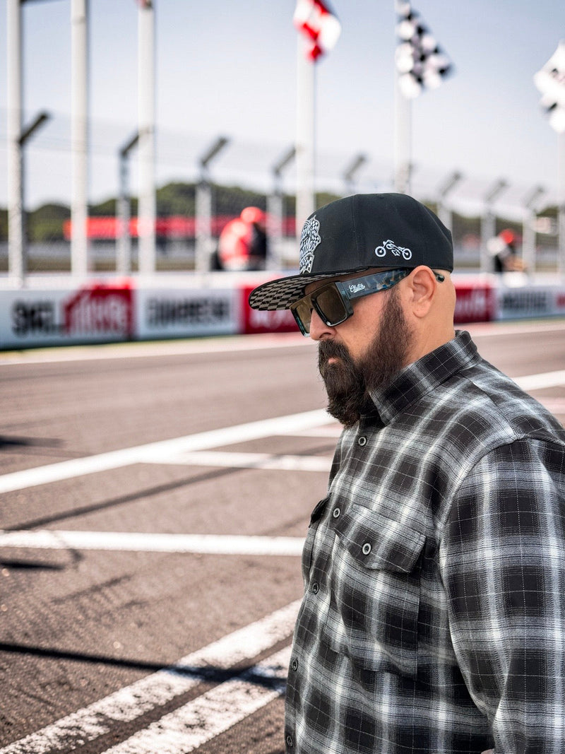 Clutch & Throttle Speed Racer Snapback at the racetrack with checkered undervisor visible