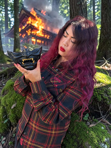 Divided Flannel Womens Hannya Flannel -  Person holding a black mask in a forest with a burning building in the background