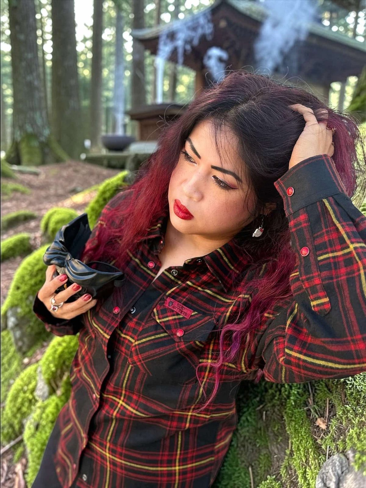 Divided Flannel Womens Hannya Flannel -  Woman in a plaid shirt with red hair and red lipstick standing in a forest.