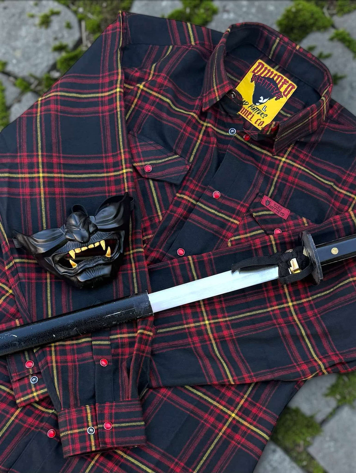 Divided Flannel Womens Hannya Flannel -  Red and black plaid shirt with samurai helmet and sword on a textured surface