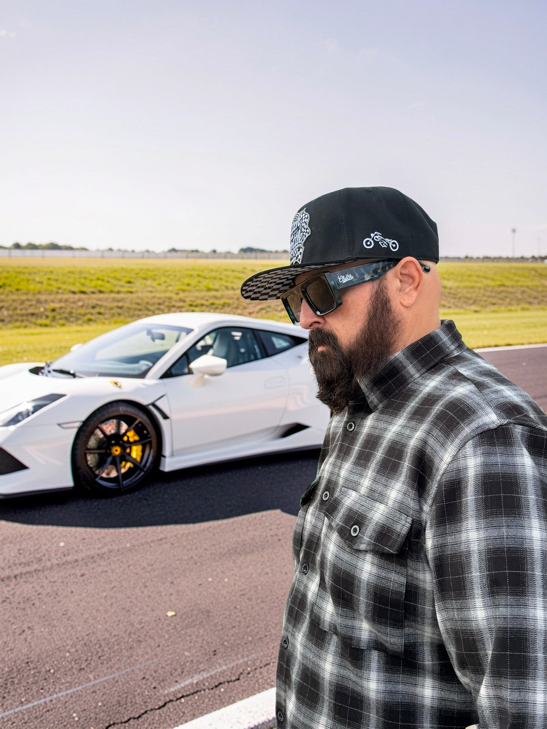 Clutch & Throttle Speed Racer Snapback worn beside a white sports car at the track